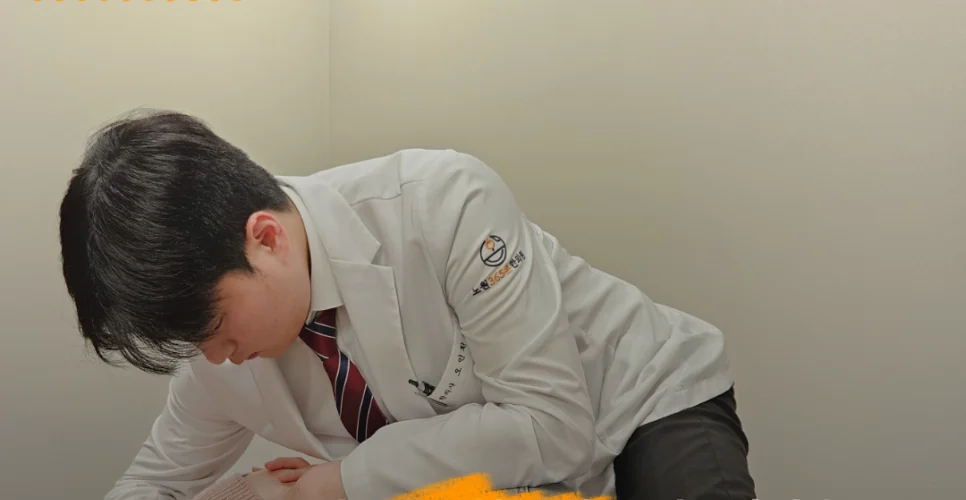 한의사가 누운 환자의 목과 어깨에 손을 대고 교정한다
